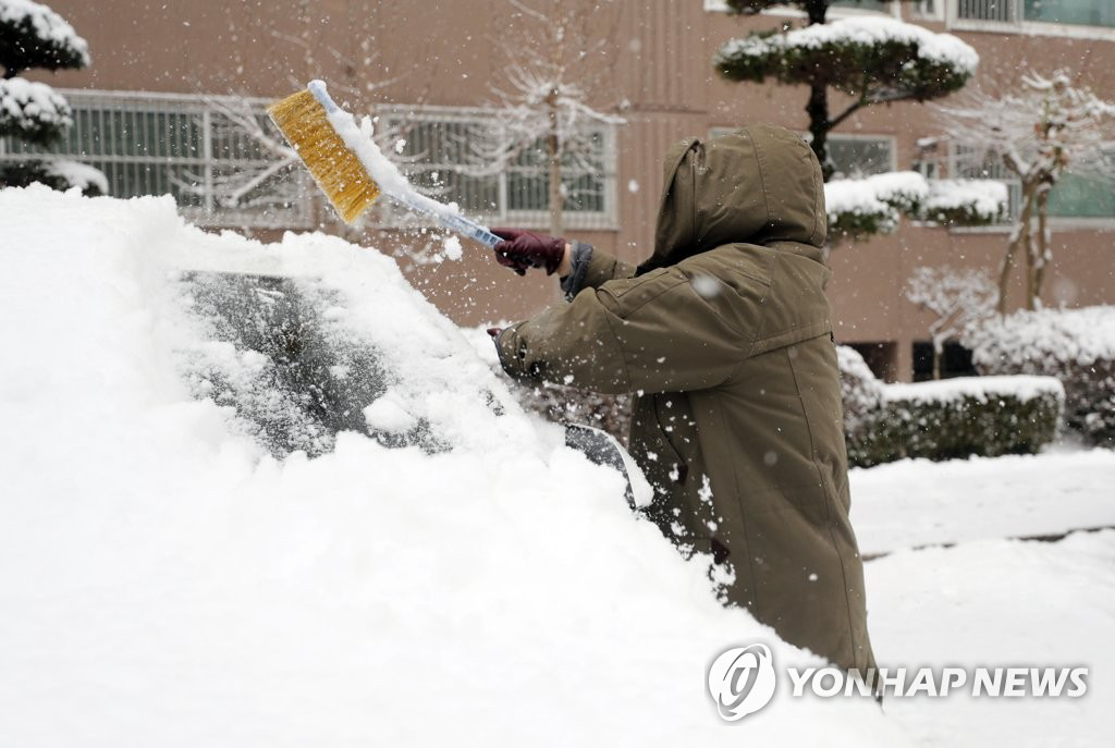 1月18日上午，全州市完山区一小区内，市民们正在清除车上的积雪。