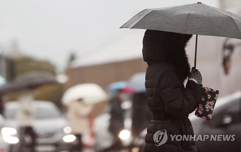 21日，韓國首爾迎來降雨，行人匆匆經過光化門前的十字路口。