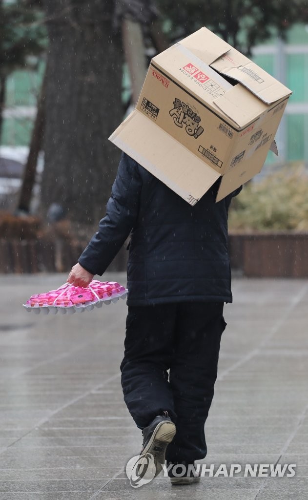 21日，首爾市一家大型超市前，市民正用紙箱躲雨。 