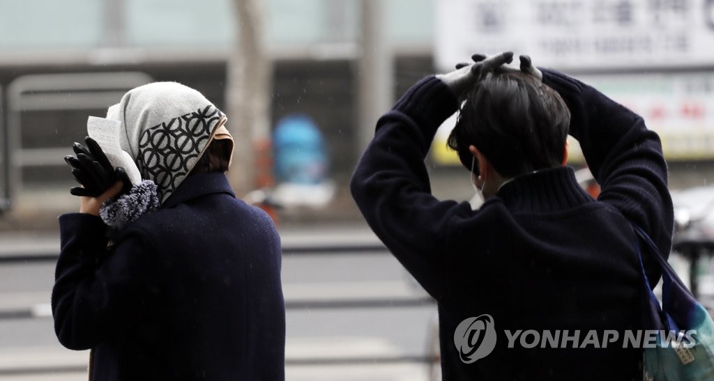 21日，首爾市，一位市民用手遮雨。