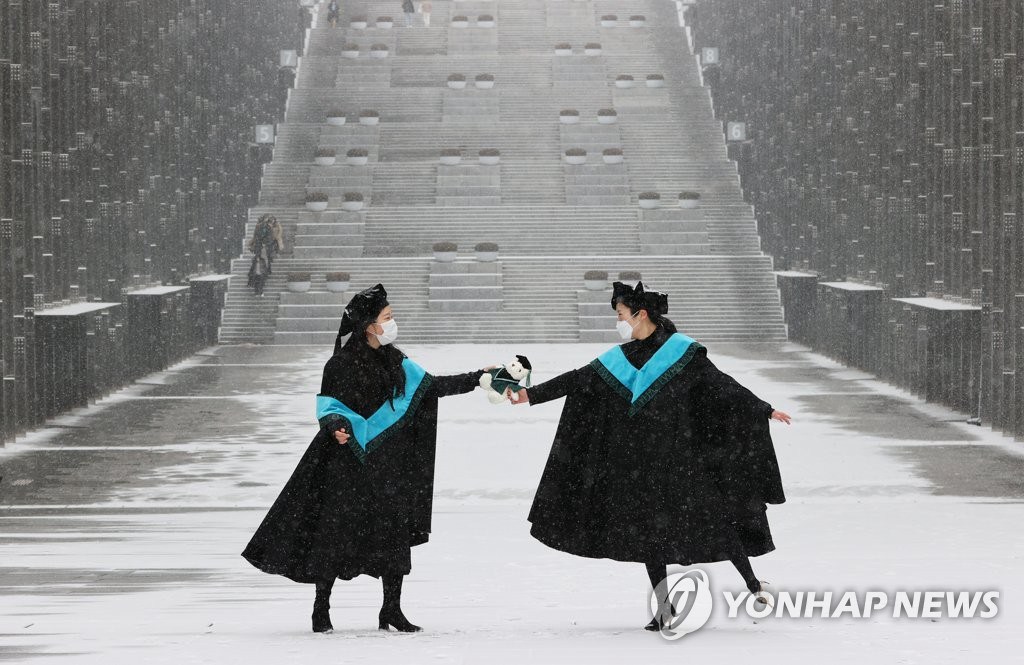 2月16日上午，在首爾西大門區梨花女子大學校園內，畢業生正在雪景中拍攝畢業照。