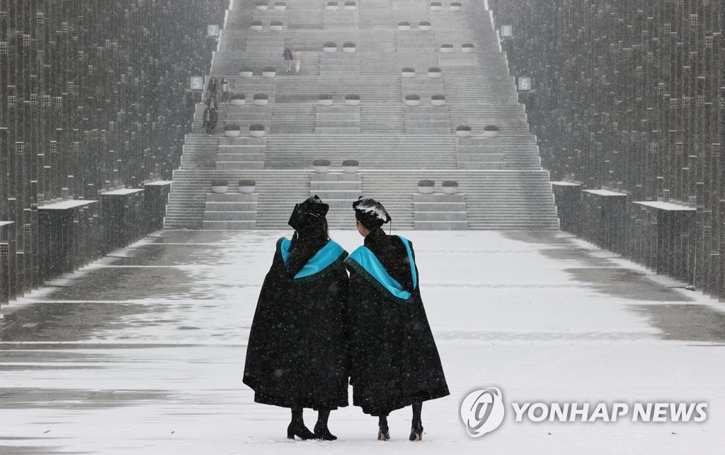 2月16日上午，在首爾西大門區梨花女子大學校園內，畢業生正在雪景中拍攝畢業照。