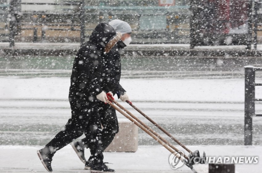 19日上午，首尔市光化门十字路口附近的市民正在清理积雪。