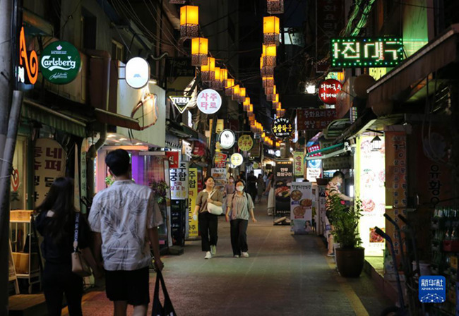 7月18日，人們走在韓國首爾的一條餐飲街上。