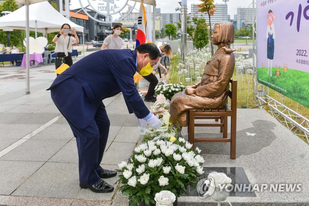 8月14日，日军“慰安妇”纪念日活动在韩国束草青草湖公园和平少女像前举行。图为束草市市长李秉宣正在献花。图源：韩联社/束草市供图