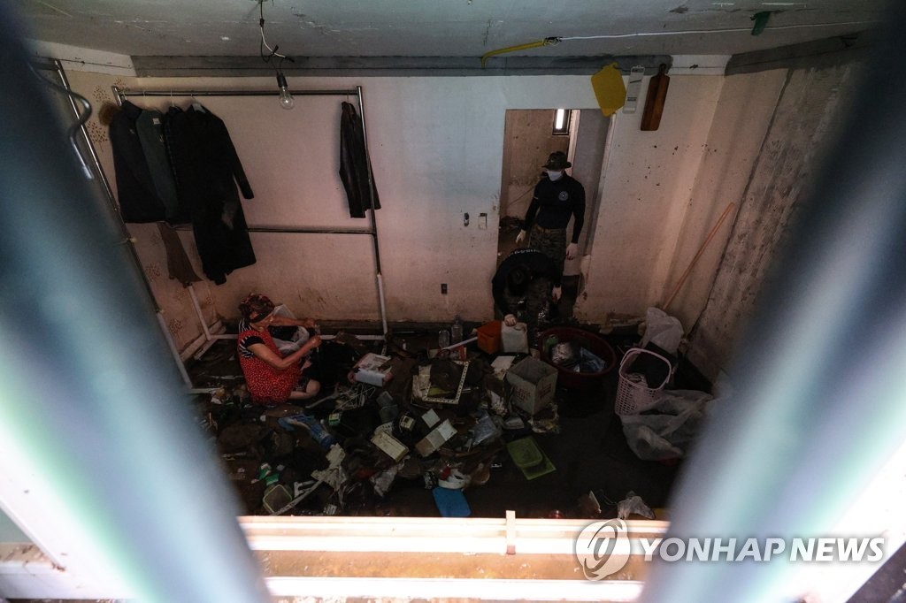 8月12日，在首尔冠岳区新林洞一处半地下住宅，韩国军人帮助灾民整理浸水物品。