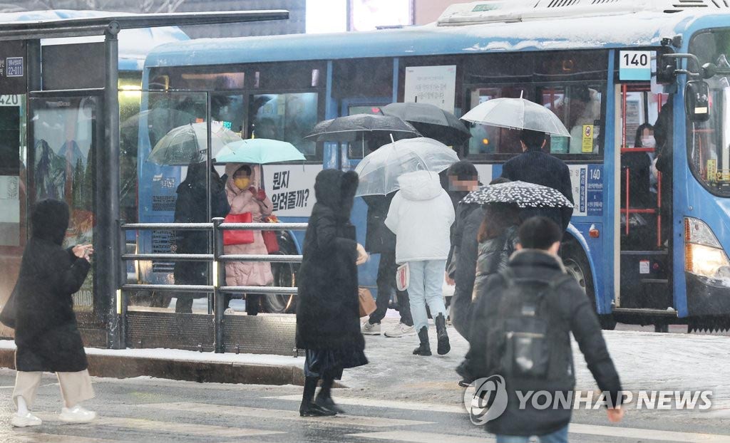 21日上午，在首尔市中心，市民冒雪出行。