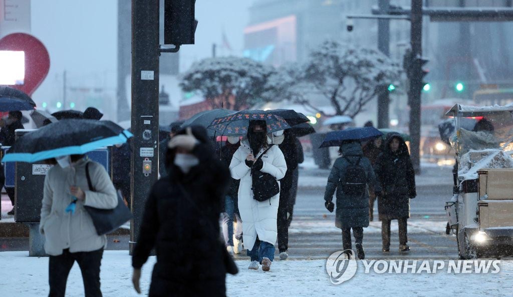 21日上午，在首尔光化门广场，市民冒雪出行。