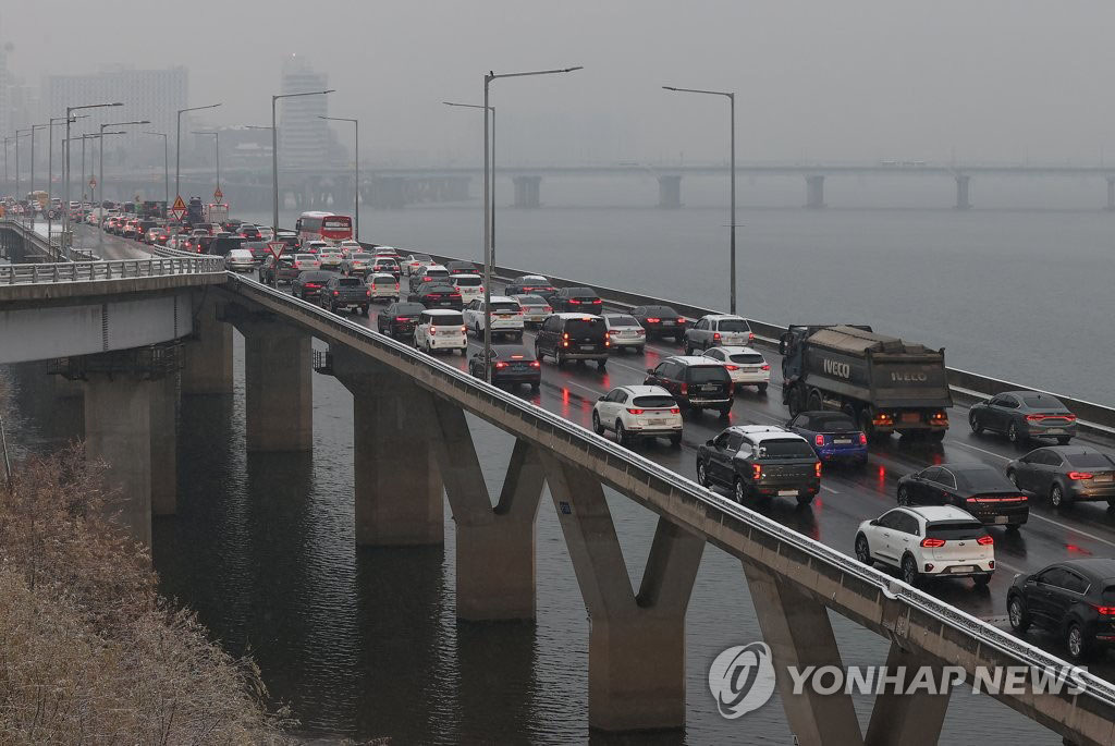 21日上午，在首尔西江大桥，受降雪天气影响，车辆在湿滑的道路上缓慢行驶。