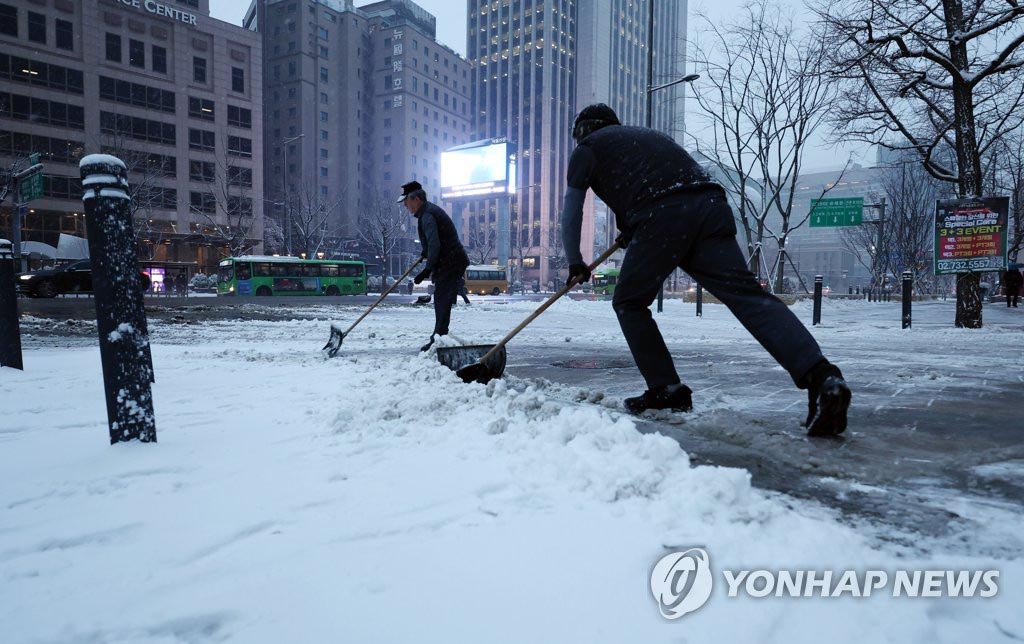  21日上午，在首尔光化门广场一带，人们正在除雪。
