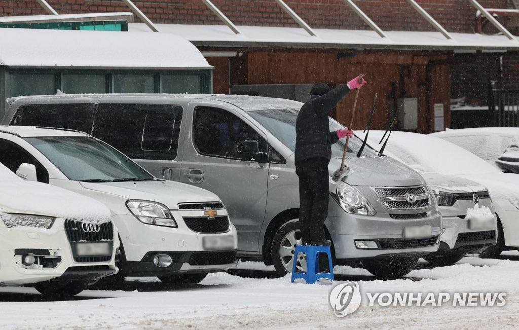 21日上午，在首尔中区药水洞，一名市民正在扫除车上的积雪。