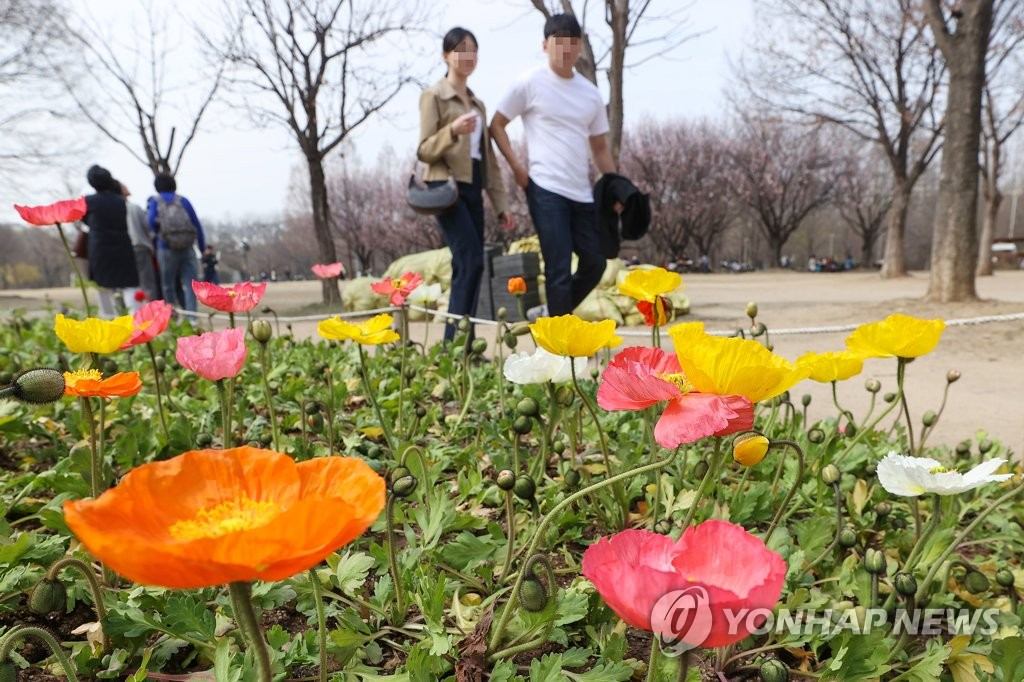 22日下午，天氣漸暖，在首爾城東區首爾林公園內，行人脫掉外衣拿在手裡。