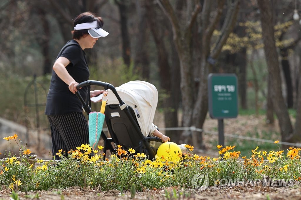 22日下午，首爾城東區首爾林公園內，一名身穿短袖的市民推著嬰兒車。