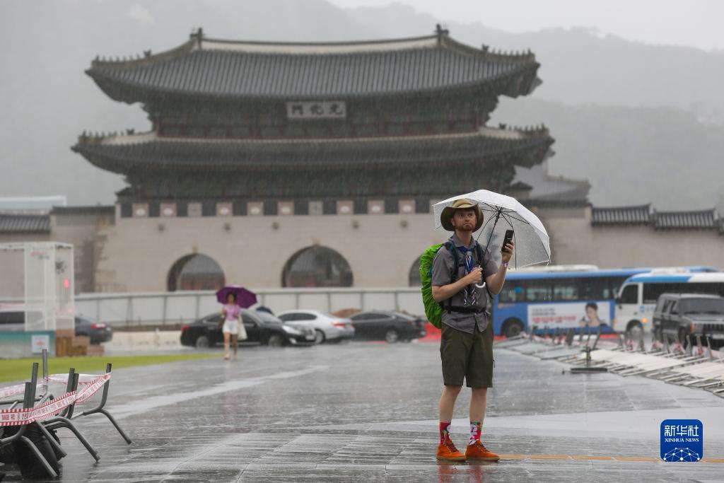 8月10日，游客撐傘走在韓國首爾光化門廣場。新華社記者 王益亮 攝