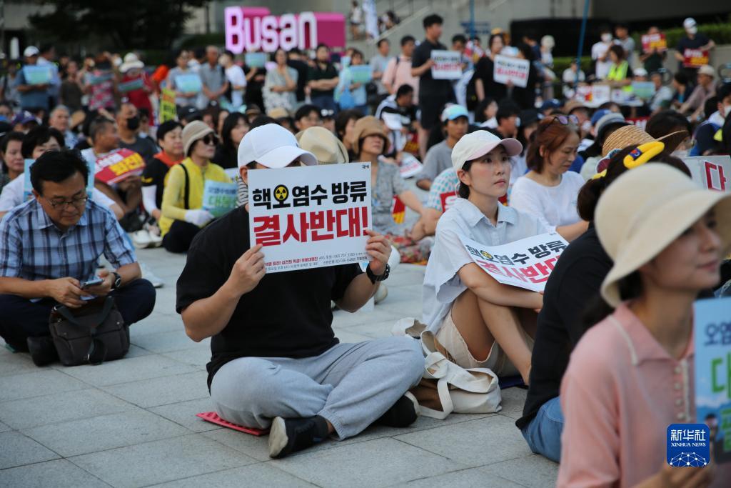 8月26日，市民手举标语在韩国釜山火车站广场前参加集会。新华社记者 陆睿 摄