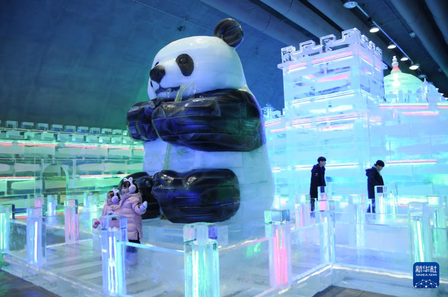 1月13日，在韓國江原道的華川山鱒魚節現場，游客在哈爾濱工匠制作的大熊貓冰雕作品前留影。