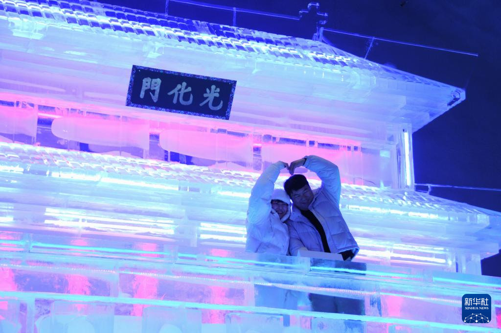 1月13日，在韓國江原道的華川山鱒魚節現場，游客在哈爾濱工匠制作的韓國光化門冰雕作品前留影。