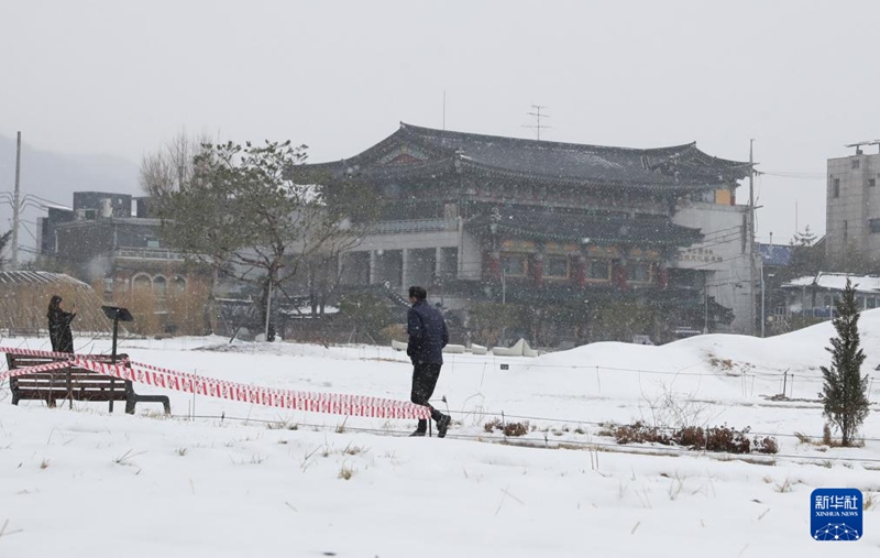 3月18日，在韩国首尔街头，市民在雪中散步。