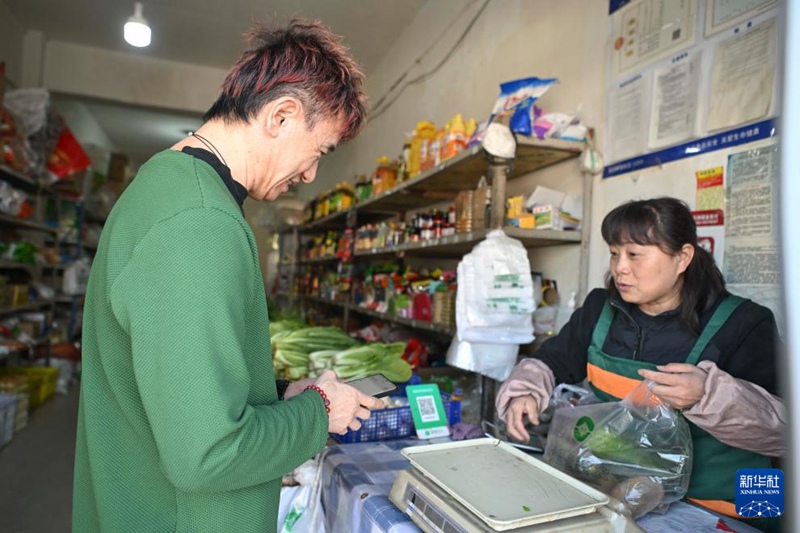 安钟旭（左）在乌鲁木齐南郊的一家商店买菜（3月18日摄）。