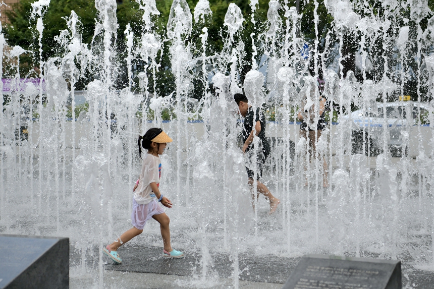 8月4日，孩子们在喷涌的水柱间欢快地穿梭奔跑。丛晨晨 摄