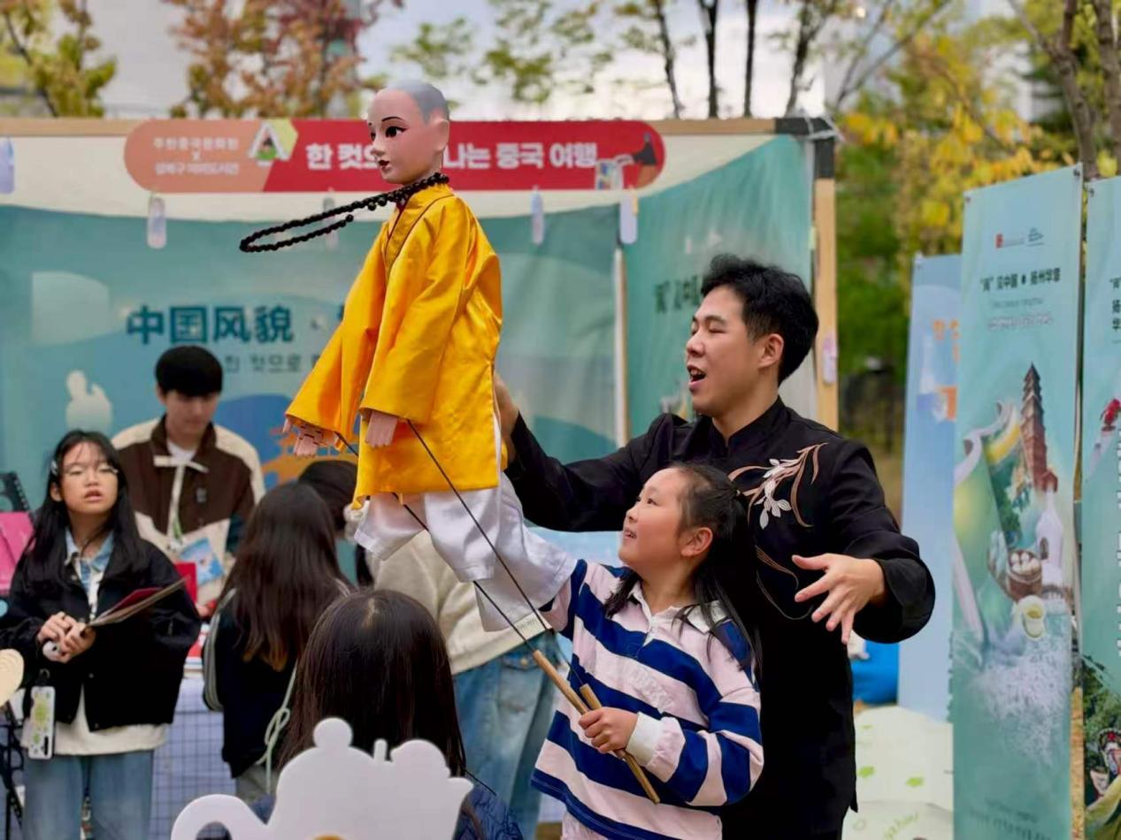 木偶戏老师手把手指导小女孩操控木偶。主办方供图
