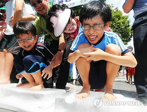 【组图】高温天气持续 韩国儿童站冰块上消暑