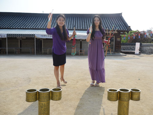 游客在首尔南山谷韩屋村玩投壶游戏。