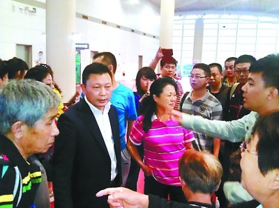 海南乐游国际旅行社有限公司郑黎东（左二）被游客围住指责