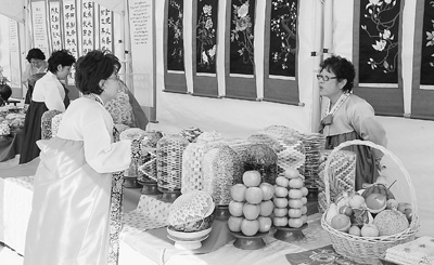 图为：一位身着韩服的妇女在韩国传统婚丧嫁娶所需的糕点展台前问询。 （万宇 摄）