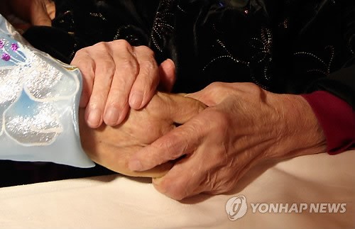 母亲紧紧握住女儿的手 （图片来源：韩联社）