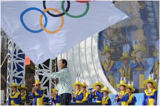 26日，江原道道知事崔文洵在江原道政府广场特色舞台活动现场挥舞奥运五环旗。